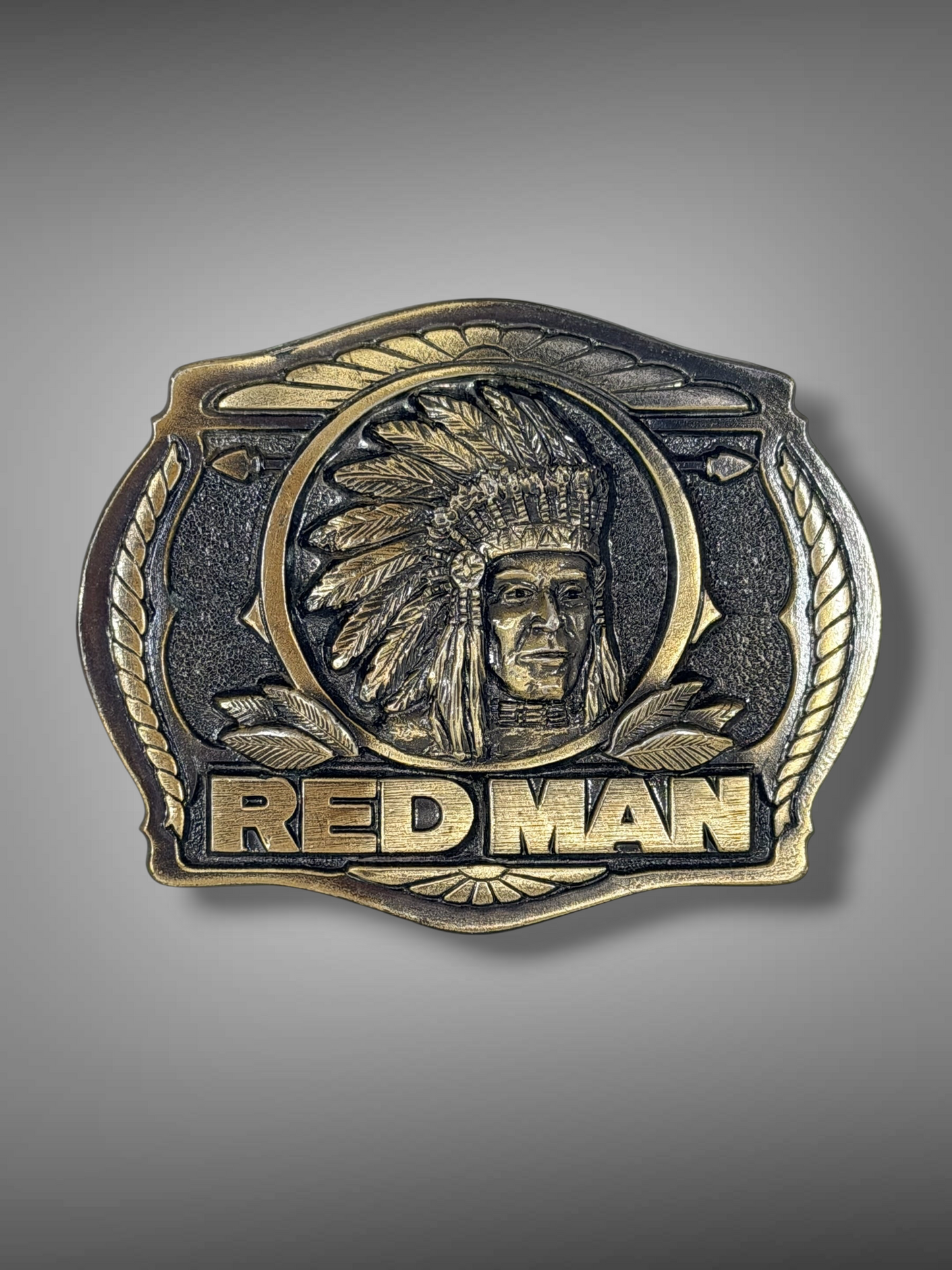 Brass Monkey Vintage 1988 Red Man belt buckle in antique brass with a Native American relief and rope-style border.